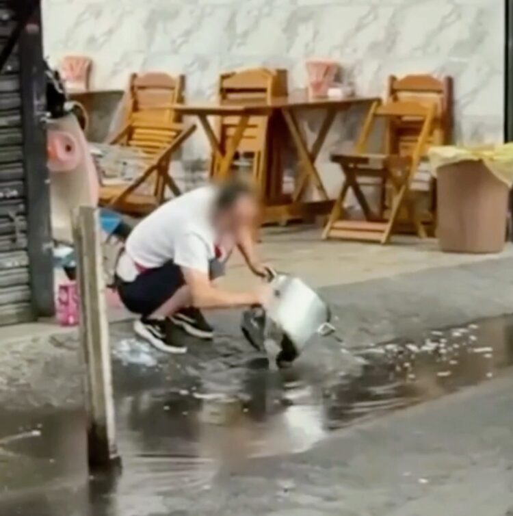 Homem chama atenção ao lavar panelas com água de poça no bairro do Brás, em São Paulo