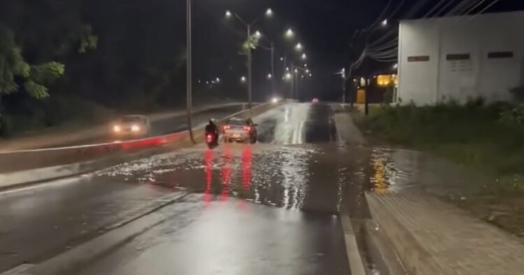 Motociclista para na via e resolve alagamento ao desobstruir bueiro