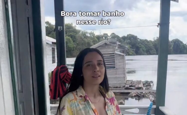 Jovem pensa em entrar no Rio Negro para aliviar o calor, mas é surpeendida ao flagrar jacaré-açu gigante